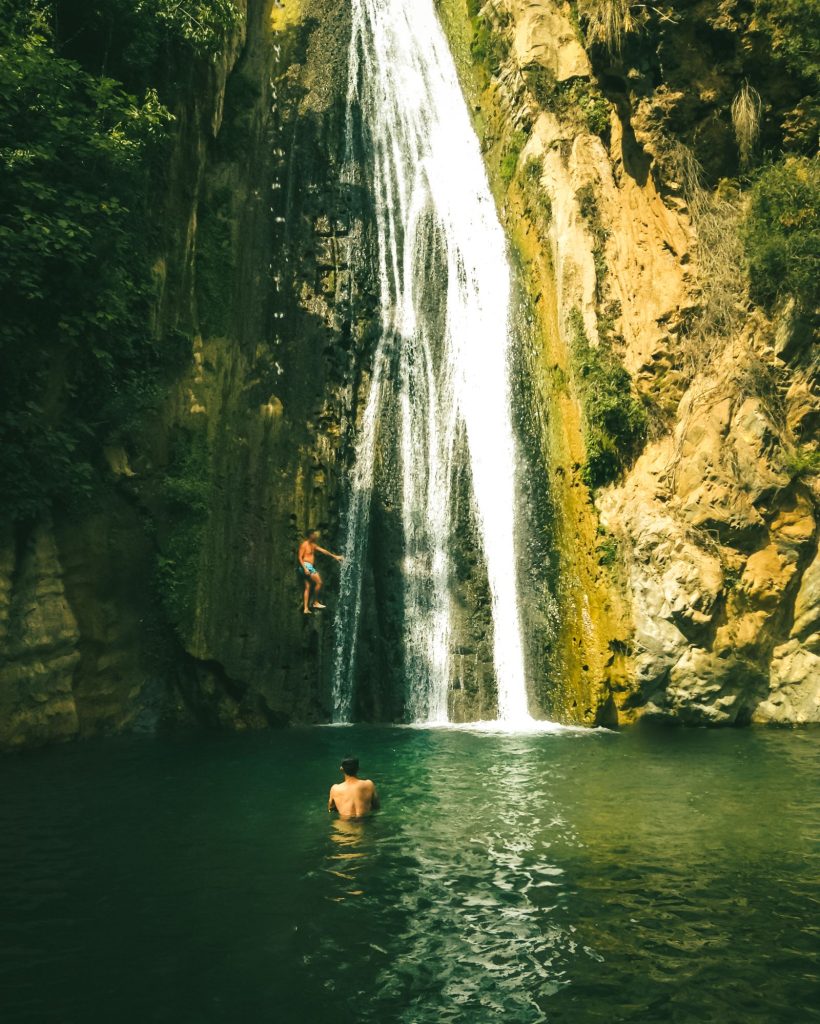 Canyonistes grimpant et se baignant au pied d'une cascade dans une gorge encaissée, canyoning aux gorges du Loup