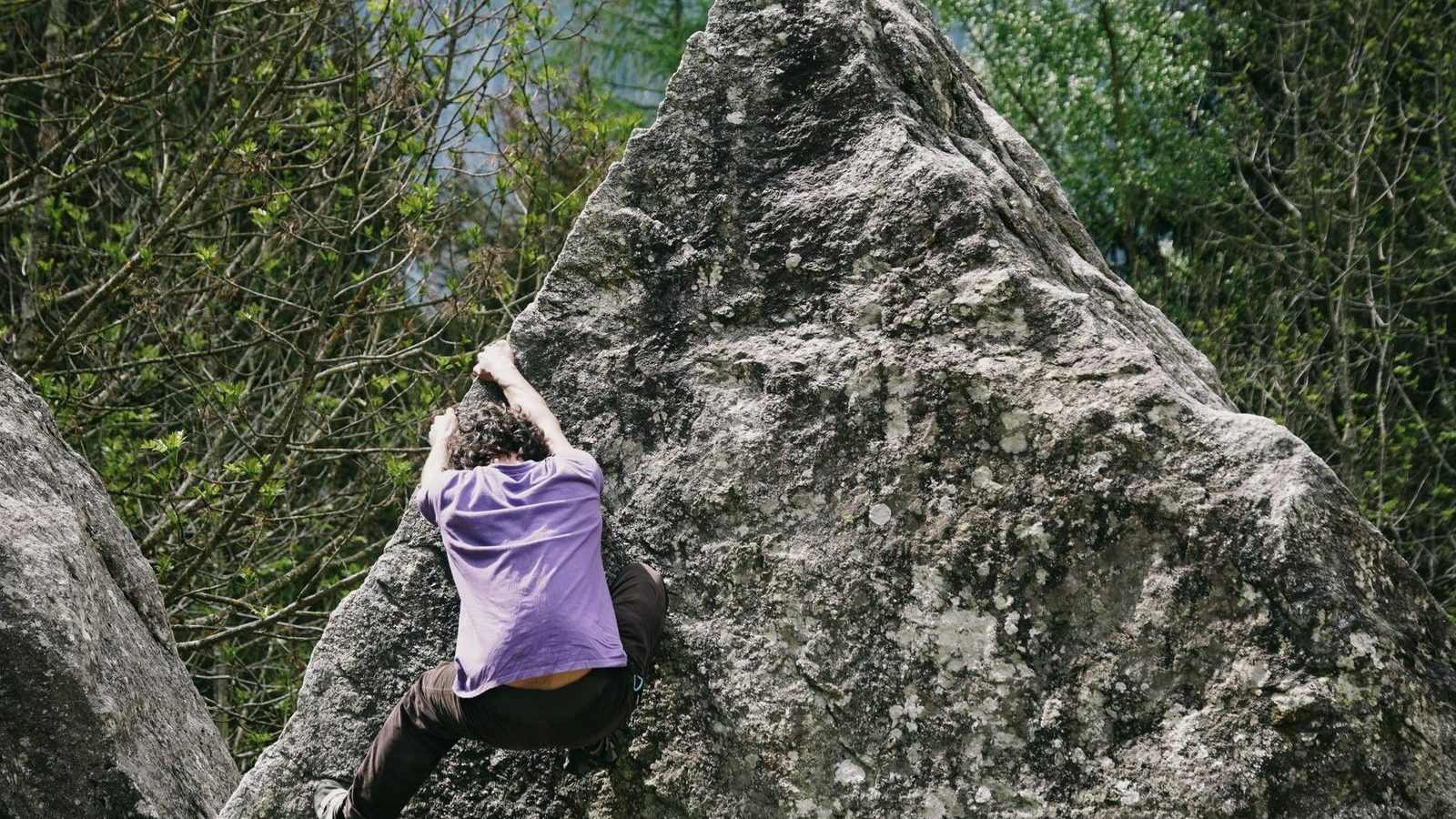 Grimpeur sur un bloc de rocher en pleine nature