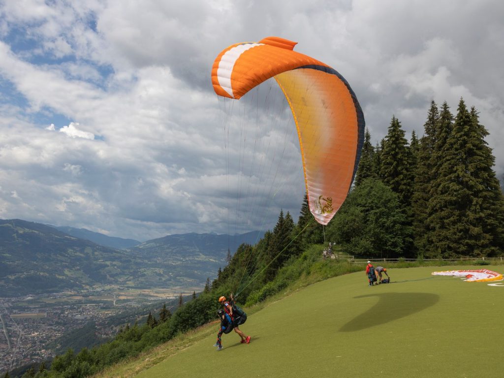 Parapentiste et son moniteur s'élançant sur une aire de décollage face à une vallée alpine, activité parapente près d'Annecy