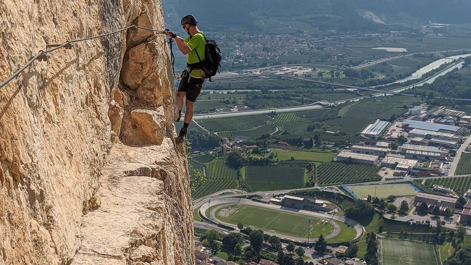 Pratiquant casqué et encordé progressant sur une paroi rocheuse équipée de câbles, via ferrata des Vosges