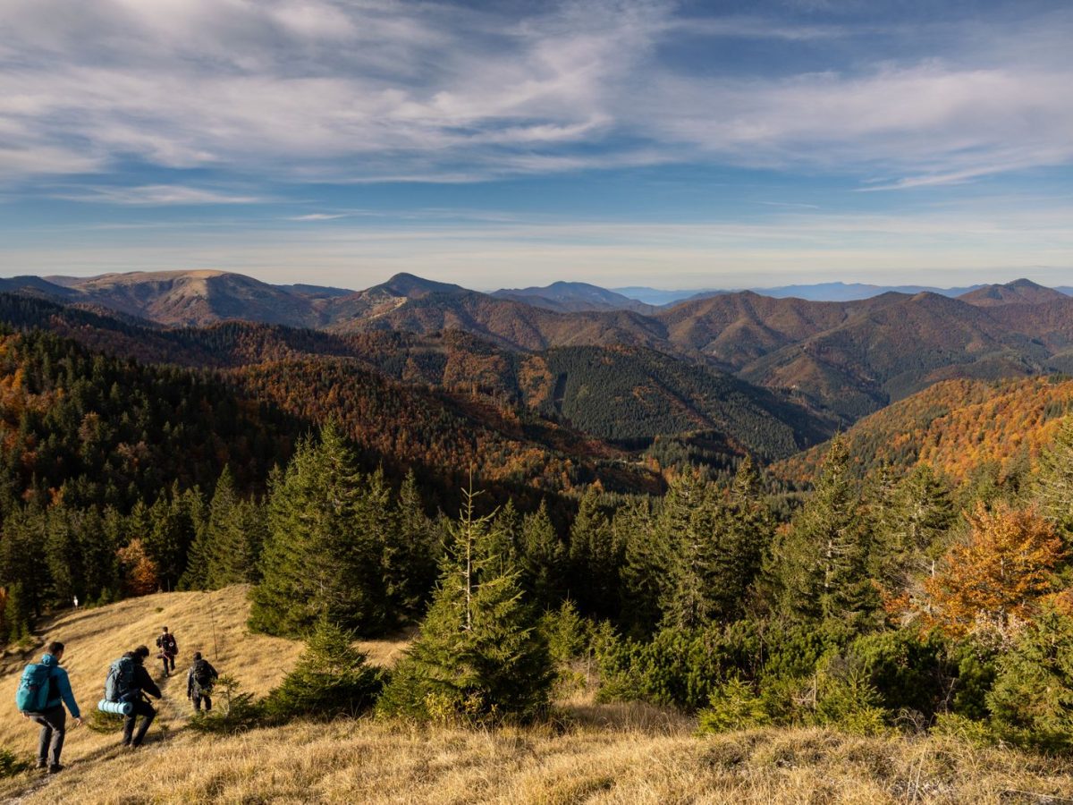 Petit groupe de randonneurs sac au dos descendant une crête avec vue panoramique sur des montagnes en automne, esprit d'équipe outdoor