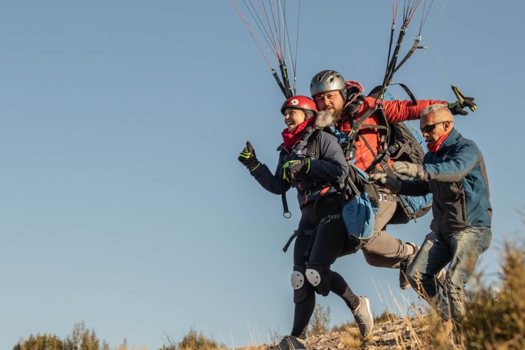 Moniteur accompagnant un passager en course de décollage biplace, harnais et voile déployée, fin de journée d'automne