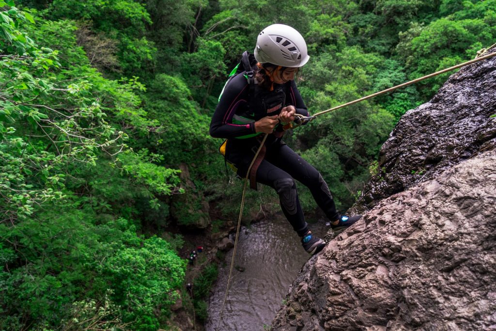 Canyoniste en rappel au-dessus d'une rivière encaissée bordée de forêt, activité canyoning près d'Annecy
