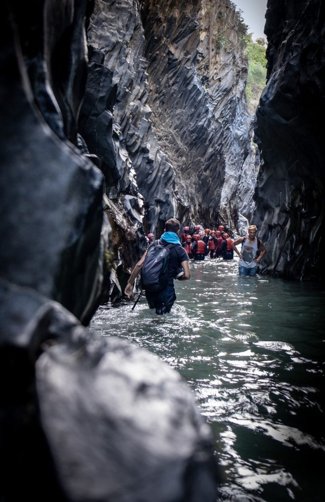 Groupe casqué en gilet équipé progressant en marchant dans l'eau d'un canyon étroit, niveau facile en canyoning débutant