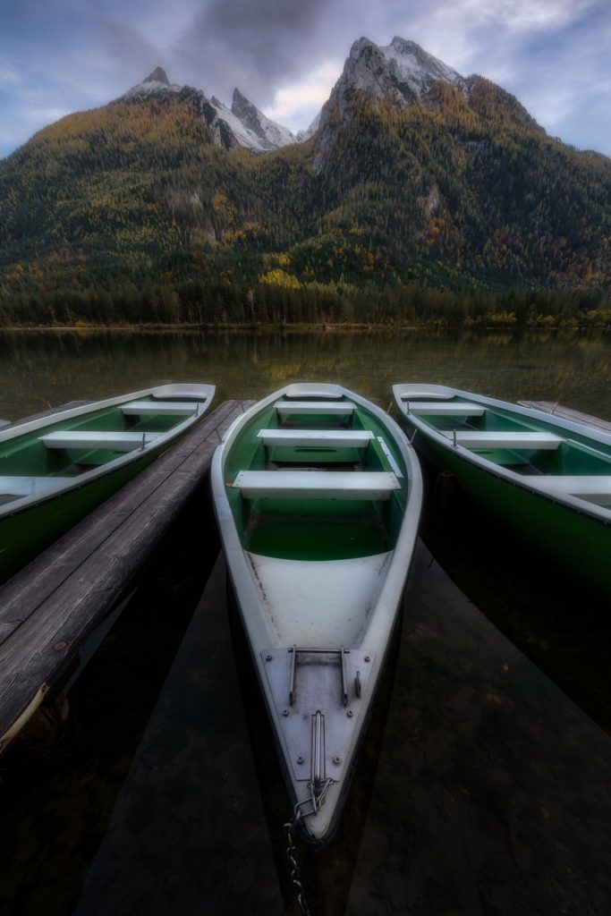 Barques de location amarrées à un ponton sur un lac de montagne entouré de sommets en automne, illustration location de bateau à Aix-les-Bains