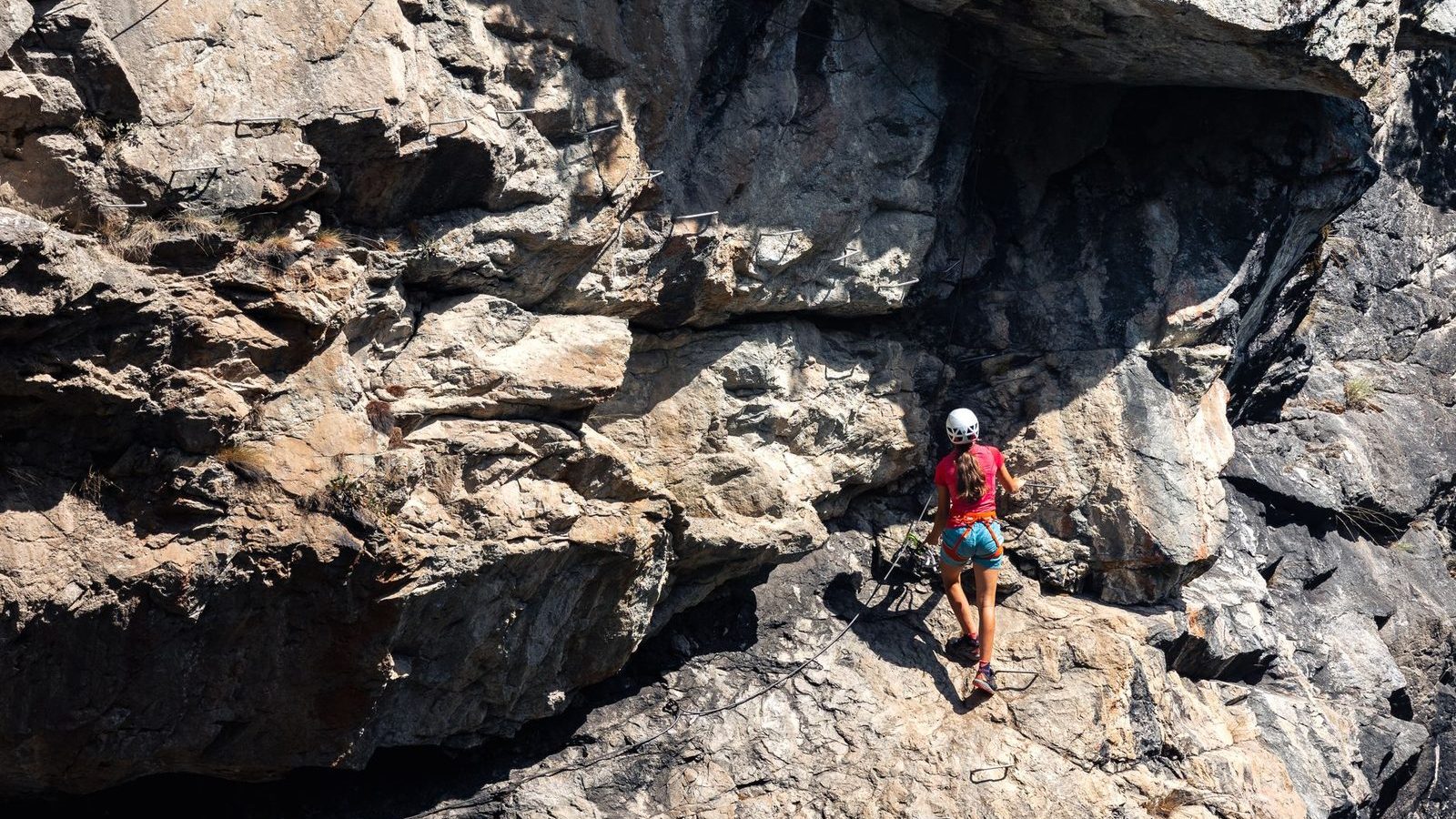 Grimpeur sur un parcours de via ferrata, cable en paroi rocheuse