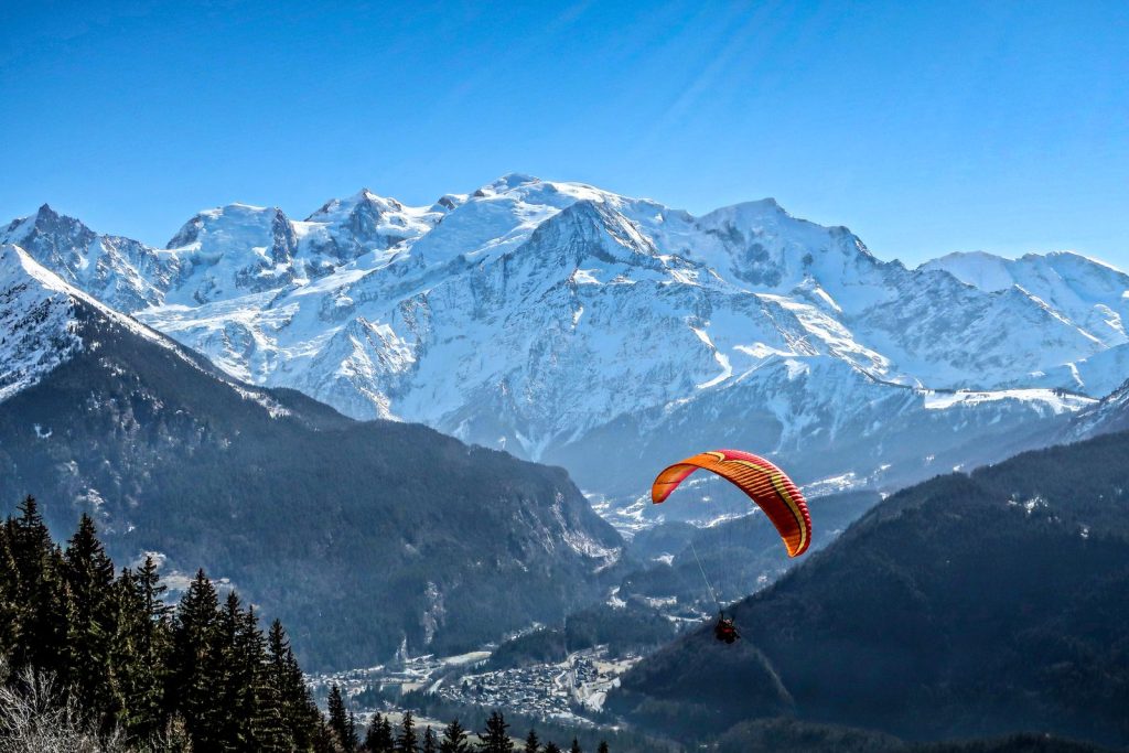 Parapente biplace survolant la vallée de Chamonix avec le massif du Mont-Blanc enneigé en arrière-plan, illustration du parapente à Chamonix