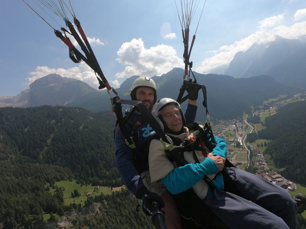 Vol biplace en parapente avec un moniteur au-dessus d'une vallée verdoyante et d'un village, activité parapente au Verdon