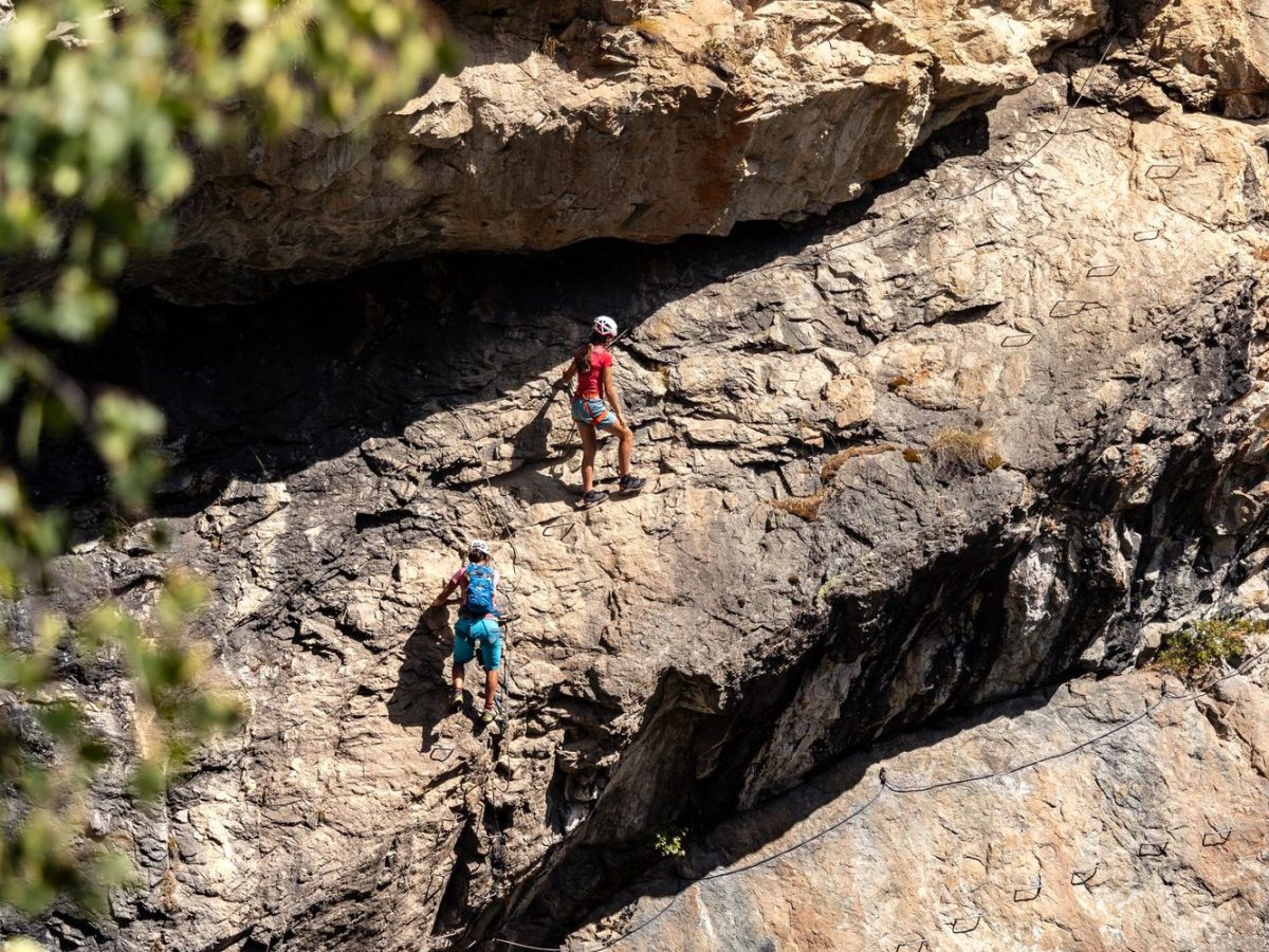 Deux grimpeurs sur une via ferrata en falaise, vue de loin