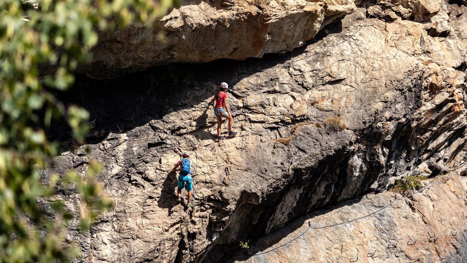 Deux grimpeurs sur une via ferrata en falaise, vue de loin