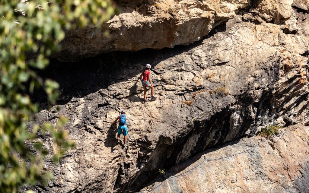 Deux pratiquants casqués progressant en encordement sur une paroi rocheuse équipée d'un câble de via ferrata, illustration de la via ferrata en Isère