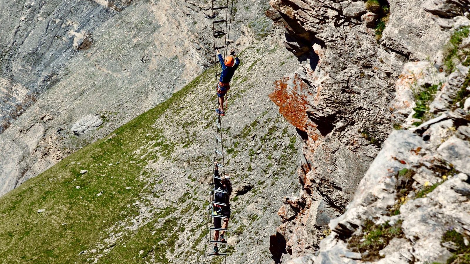 Grimpeur progressant sur une echelle de via ferrata en montagne