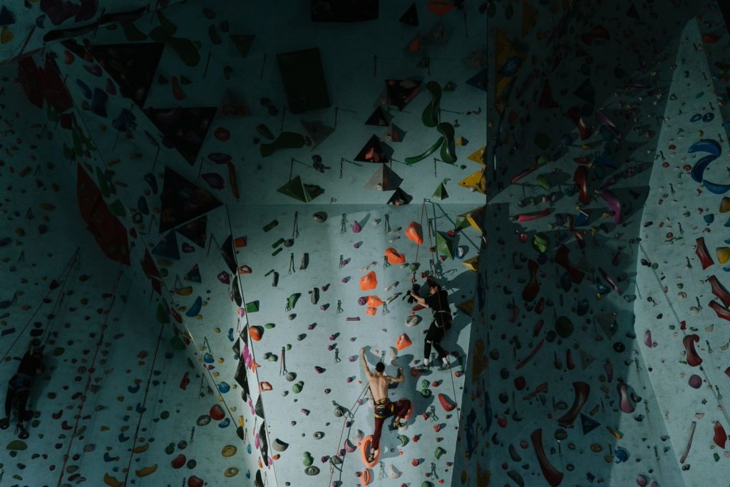 Grimpeurs en compétition sur un mur d'escalade indoor aux prises colorées, ambiance championnat d'escalade