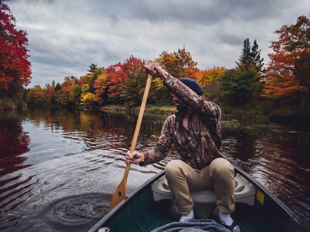 Pagayeur en canoë sur une rivière calme bordée de forêts aux couleurs d'automne, illustration du canoë en Dordogne