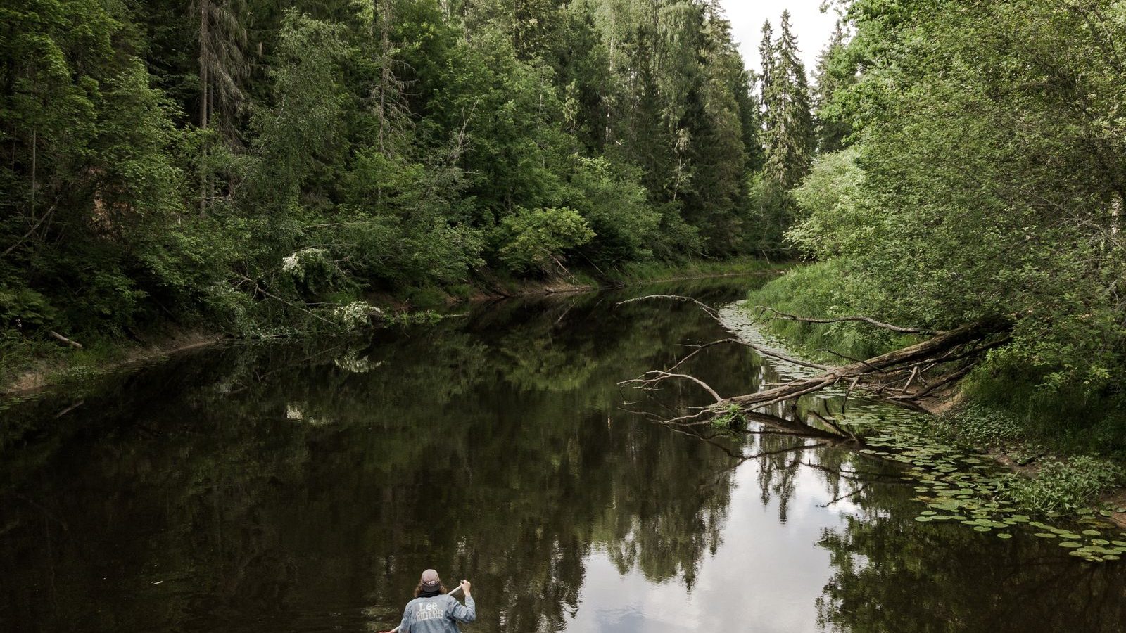 Deux pagayeurs en canoë sur une rivière calme bordée de forêt, activité canoë en Dordogne