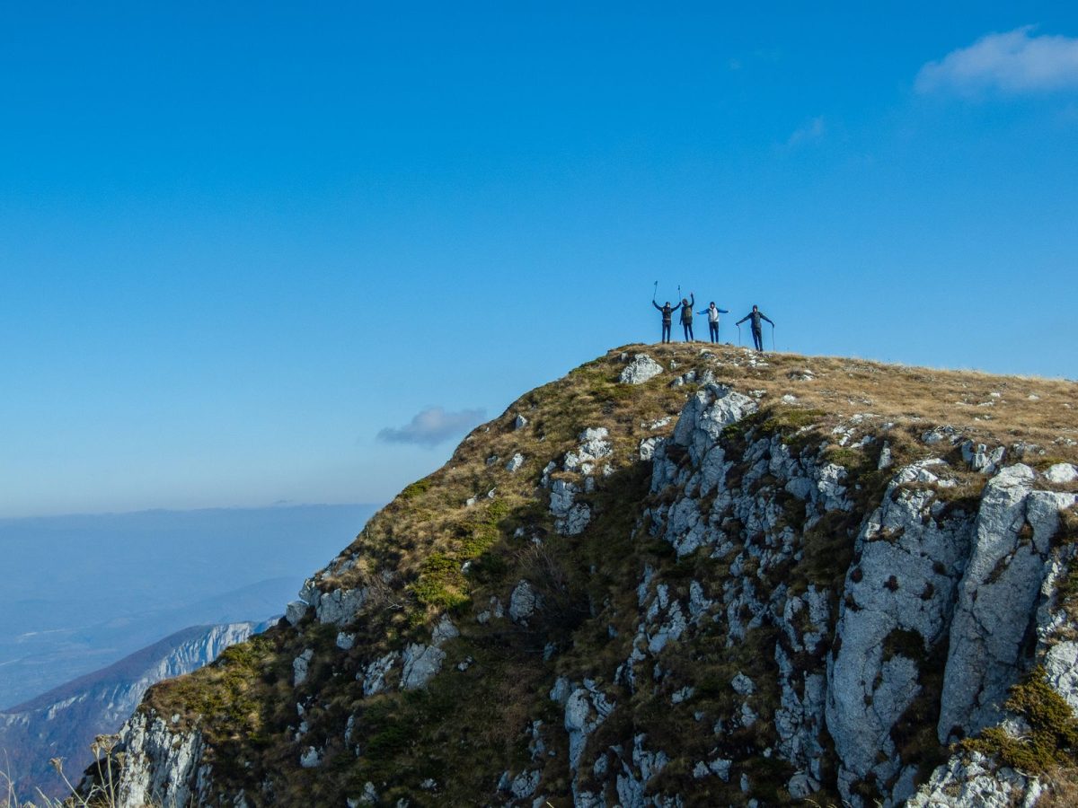 Groupe d'amis bras levés en signe de victoire au sommet d'une montagne, ambiance enterrement de vie de garçon en plein air