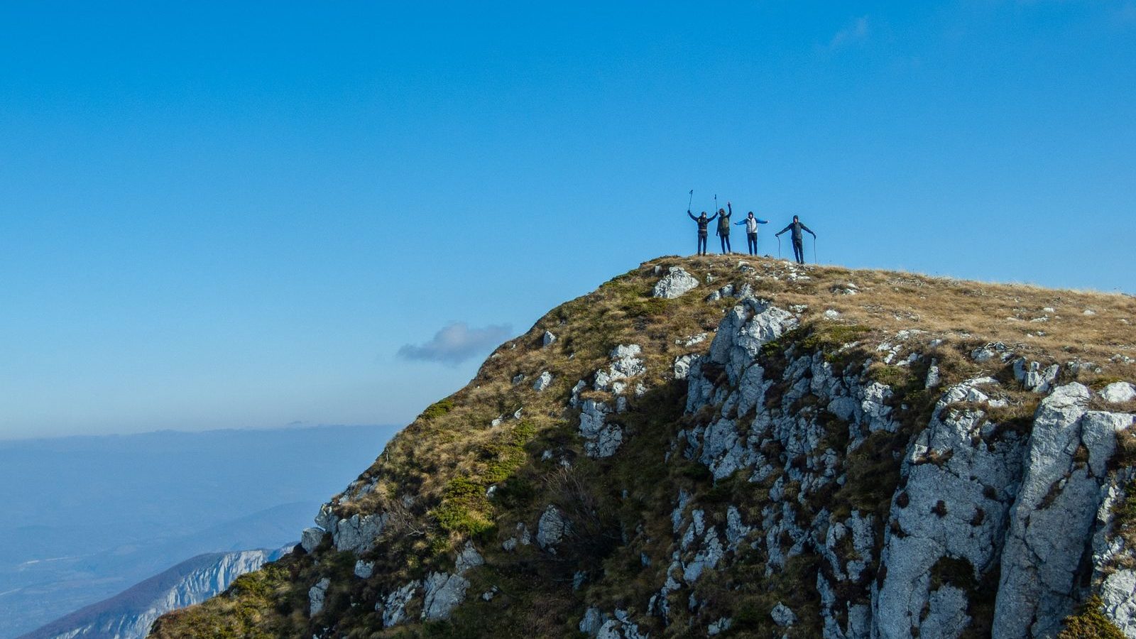 Groupe d'amis bras levés en signe de victoire au sommet d'une montagne, ambiance enterrement de vie de garçon en plein air
