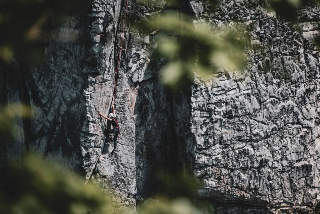 Grimpeur encordé progressant sur une falaise calcaire à l'extérieur, escalade dans les Gorges du Tarn