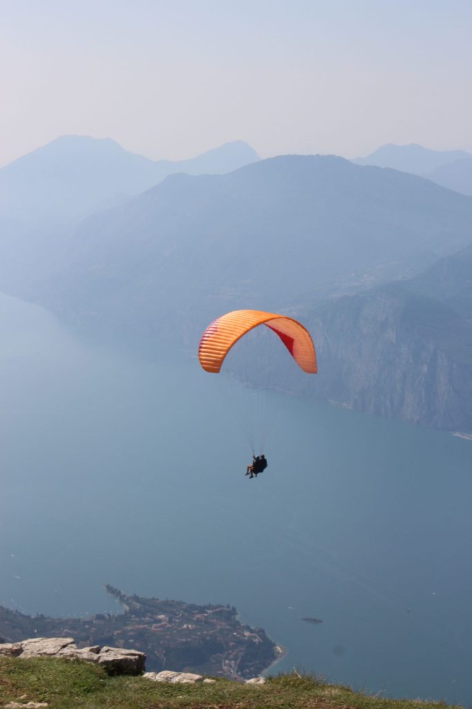 Parapente biplace survolant un grand lac entouré de montagnes, illustration d'un vol au départ de la Forclaz près du lac d'Annecy