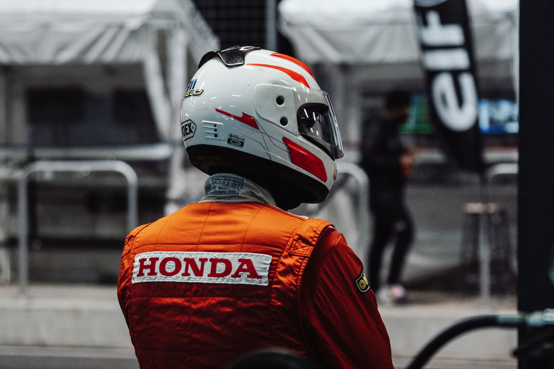 pilote en combinaison portant un casque, prêt pour une session sur circuit