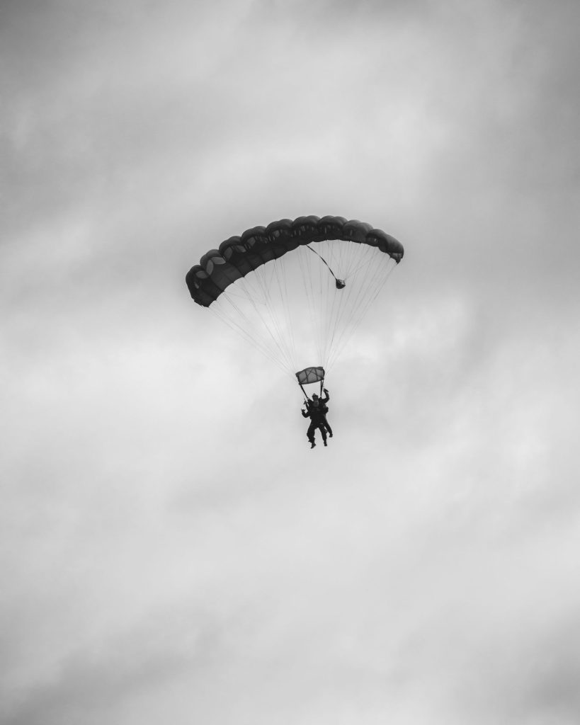 silhouette en noir et blanc d'un tandem sous voile déployée, ciel couvert