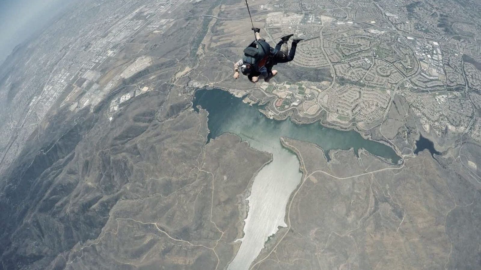 Tandem de parachutistes en chute libre au-dessus d un paysage de littoral et d un lac