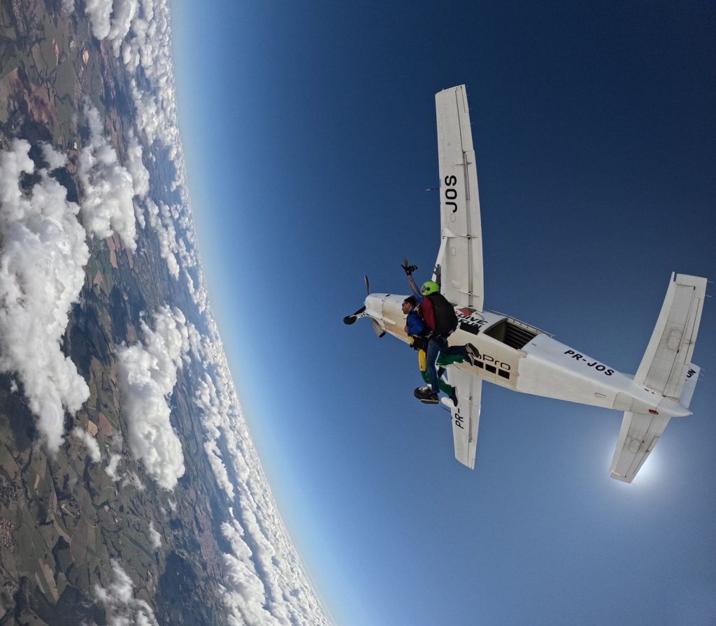 duo en tandem sautant de l'avion, vue plongeante sur la campagne et les nuages