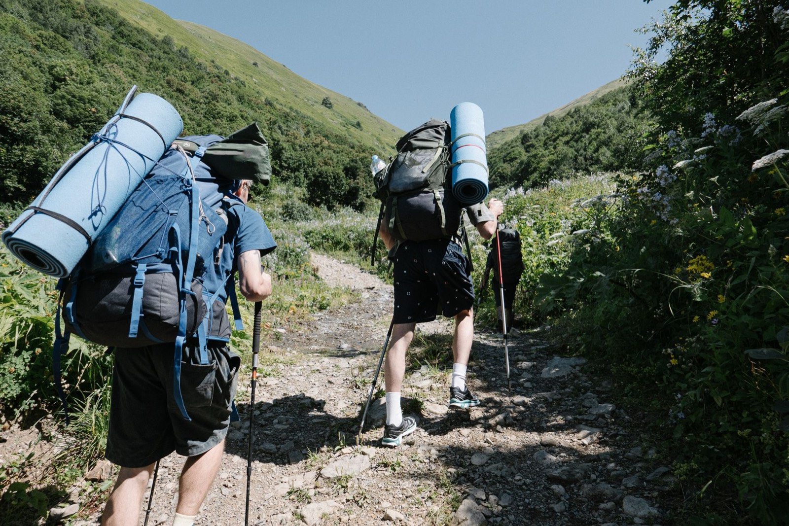 Chaussures de randonnée sur un chemin de gravier, sac à dos posé au sol, préparation d'un trek de plusieurs jours