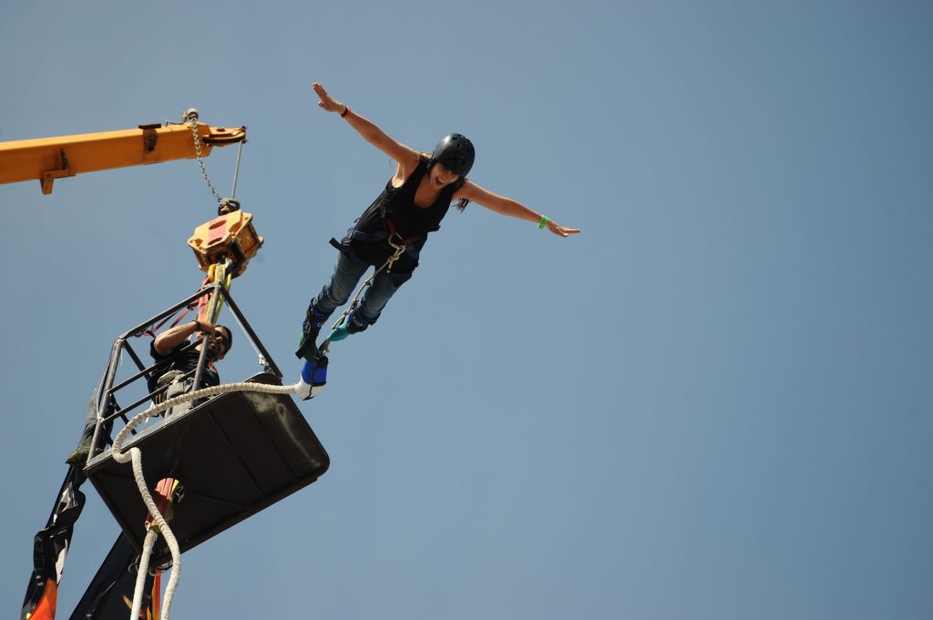 sauteuse en élastique bras écartés au moment du saut depuis une nacelle, activité à sensations fortes