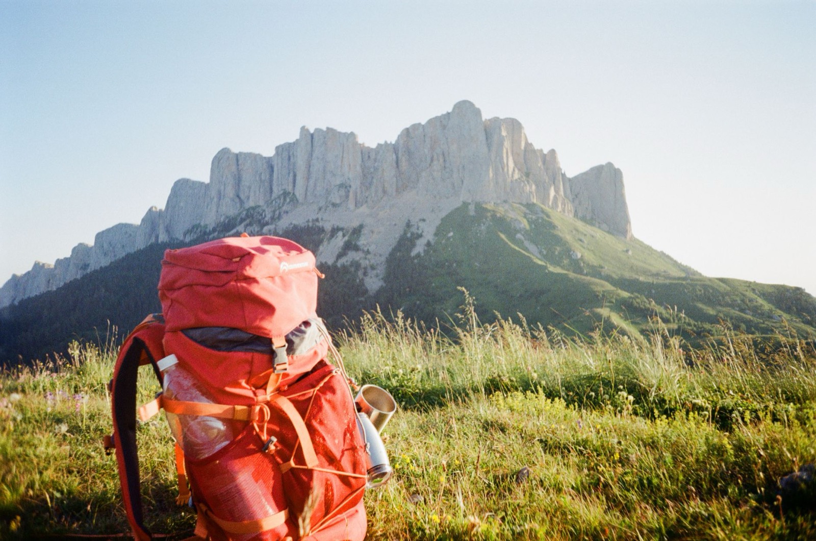 sac à dos de randonnée avec gourde posé sur un sentier de terrain aride