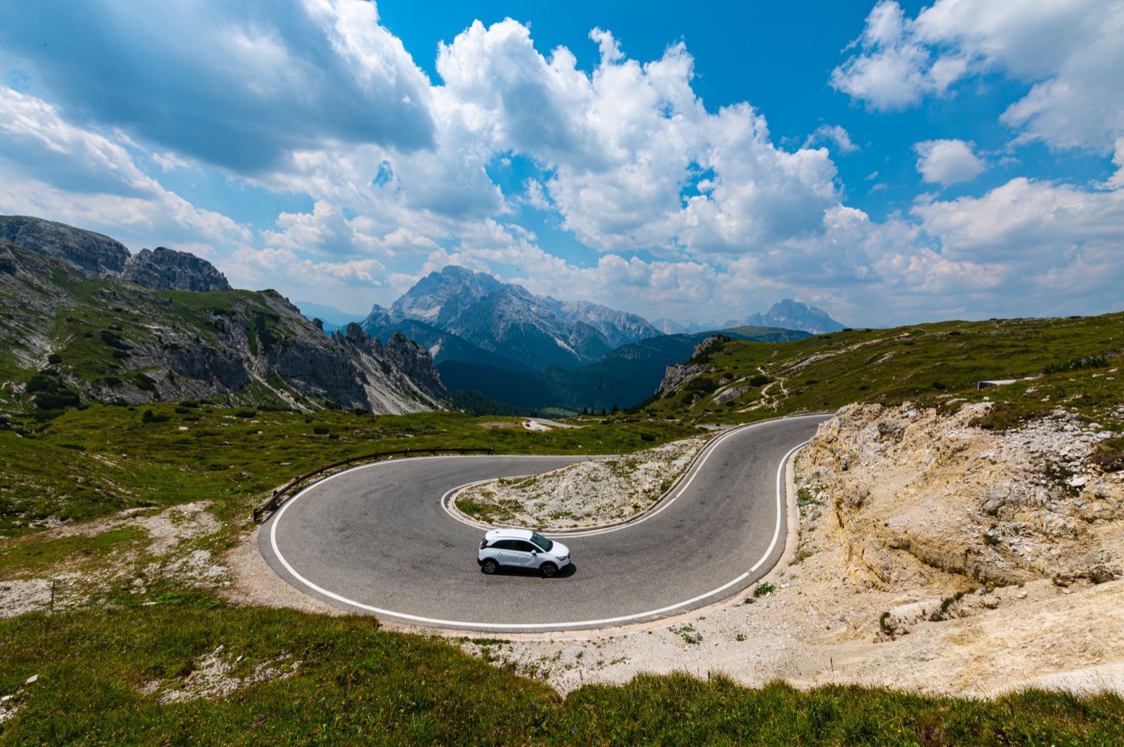 Voiture tractant une remorque dans un virage en épingle sur une route de montagne